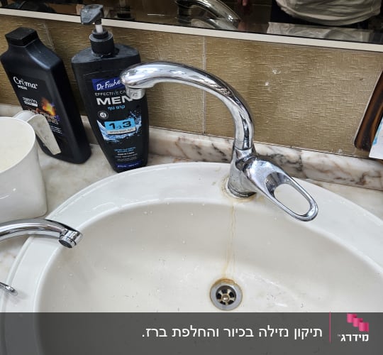 כיור עם ברז ומוצרי טיפוח בחדר אמבטיה